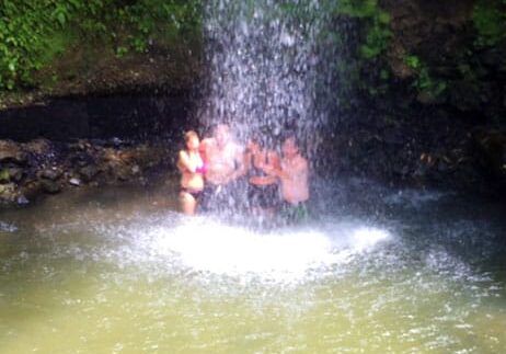 A family is cooling off under Toraille Waterfall on Spencer Ambrose Tours, St. Lucia